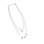 Silver-tone layered necklace with pastel teardrop crystal charms, worn on model at beach, close-up on neck