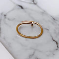 Rose gold nail cuff bracelet with screw-thread motif, worn on wrist by a pool