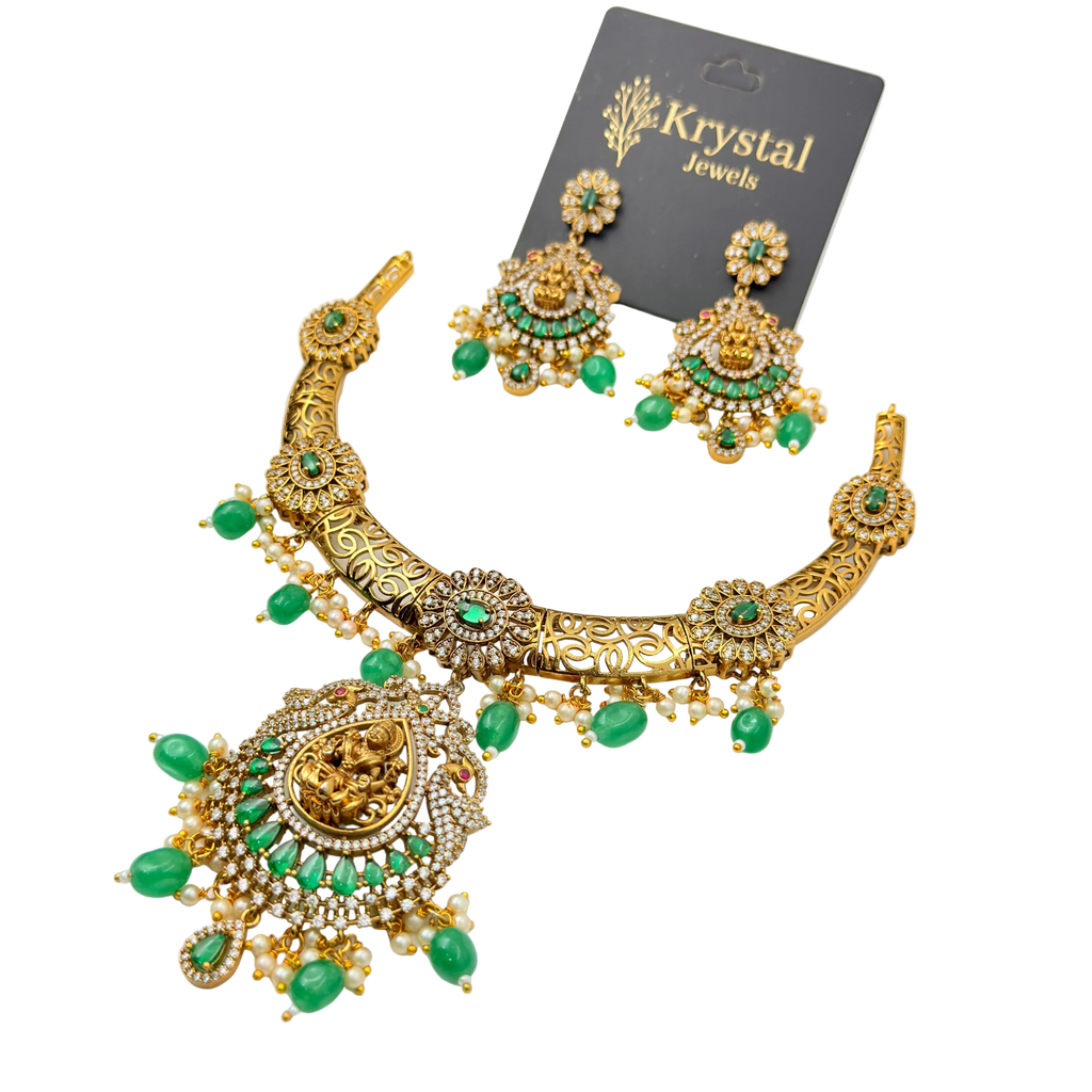 Gold necklace with green gemstones and matching earrings on a Krystal Jewels card.