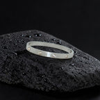 Silver bracelet with small stones on a black textured surface