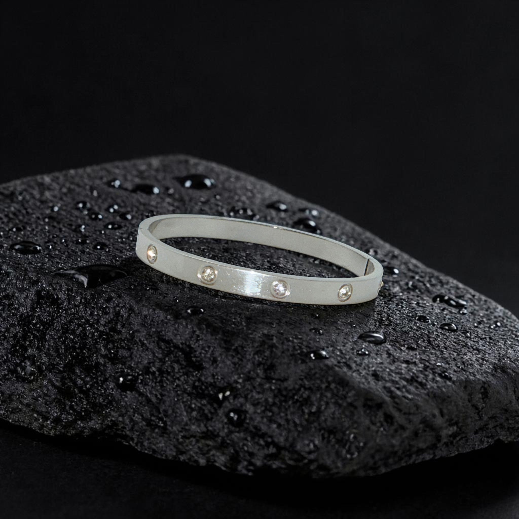 Silver bracelet with small stones on a black textured surface