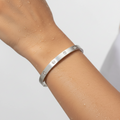 Silver bracelet with small stones on a wrist against a light background