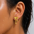 Gold earring worn by a person with a neutral background