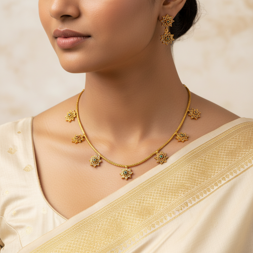 Woman wearing a gold necklace and earrings with a beige saree