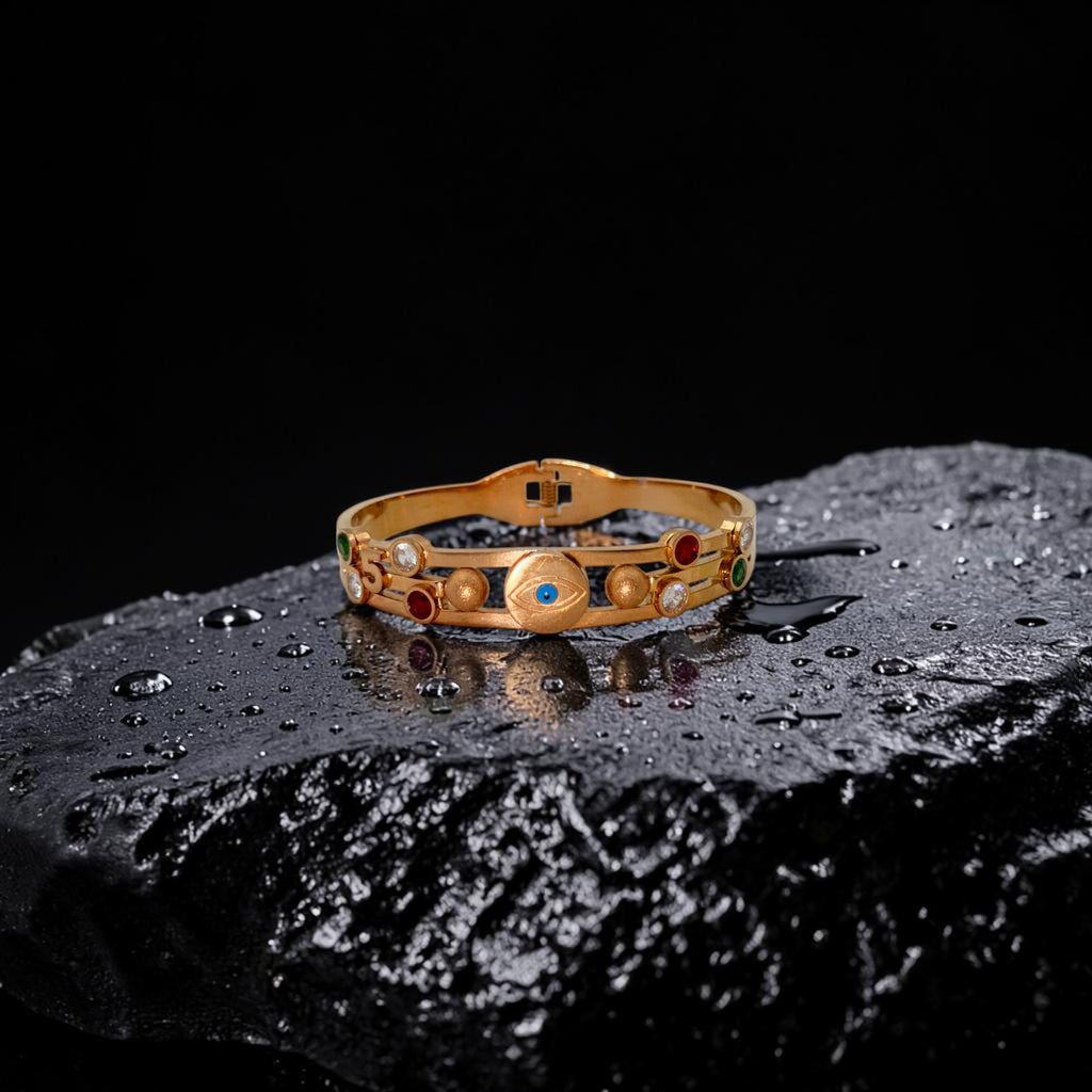 Gold bracelet with gemstones on a dark textured surface