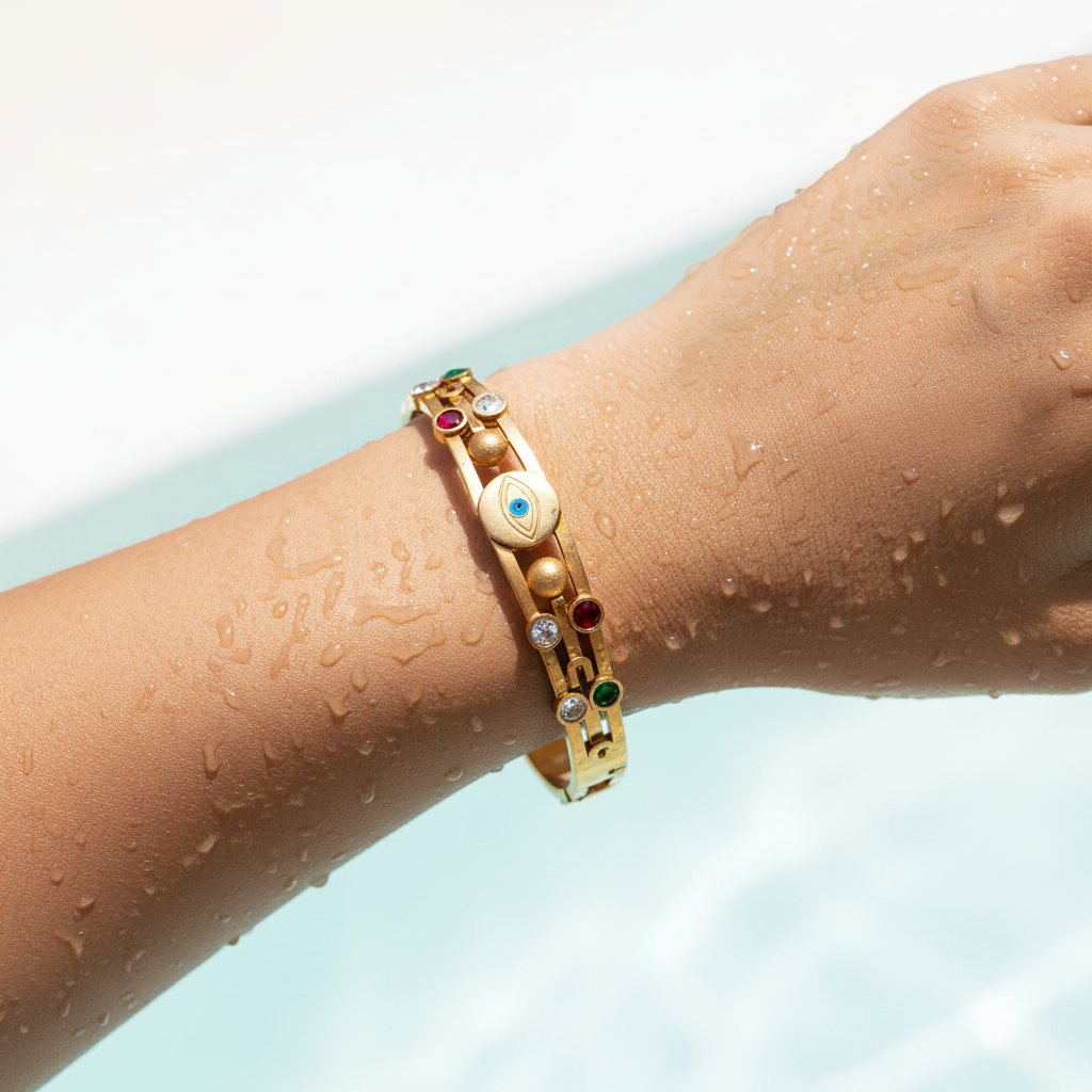 Gold bracelet with colorful stones on a wet arm against a light blue background