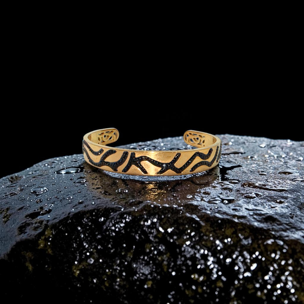 Gold bracelet with black patterns on a dark, textured surface