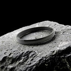 Black bracelet on a textured rock surface with water droplets