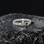 Silver bracelet with gemstones on a dark, textured surface