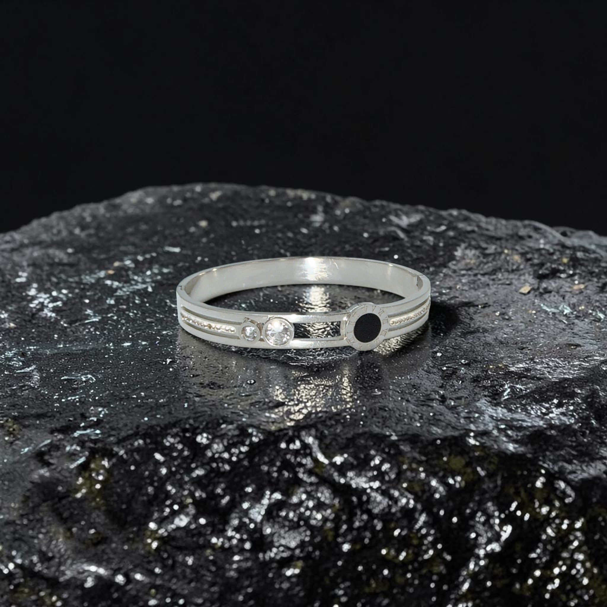 Silver bracelet with gemstones on a dark, textured surface