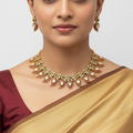 Woman wearing a gold necklace and earrings with a plain background