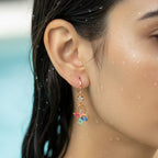 Gold-tone butterfly drop earring with pastel crystal wings, worn close-up on model's ear