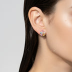 Rose-gold-tone five-petal floral stud earring with pastel pear-cut crystals, close-up worn on ear