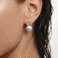 Close-up of an ear wearing a pearl earring with a gold setting.