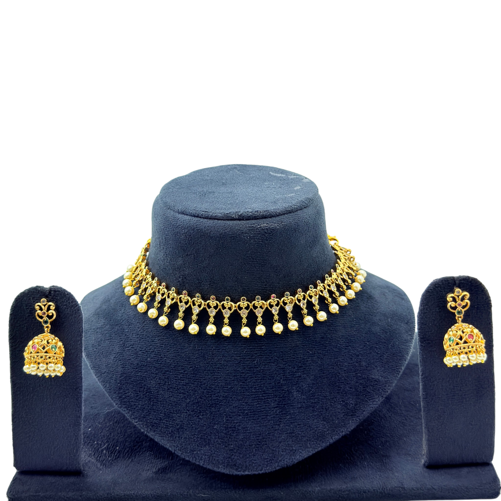 Gold necklace and earrings set on a blue velvet stand with a white background