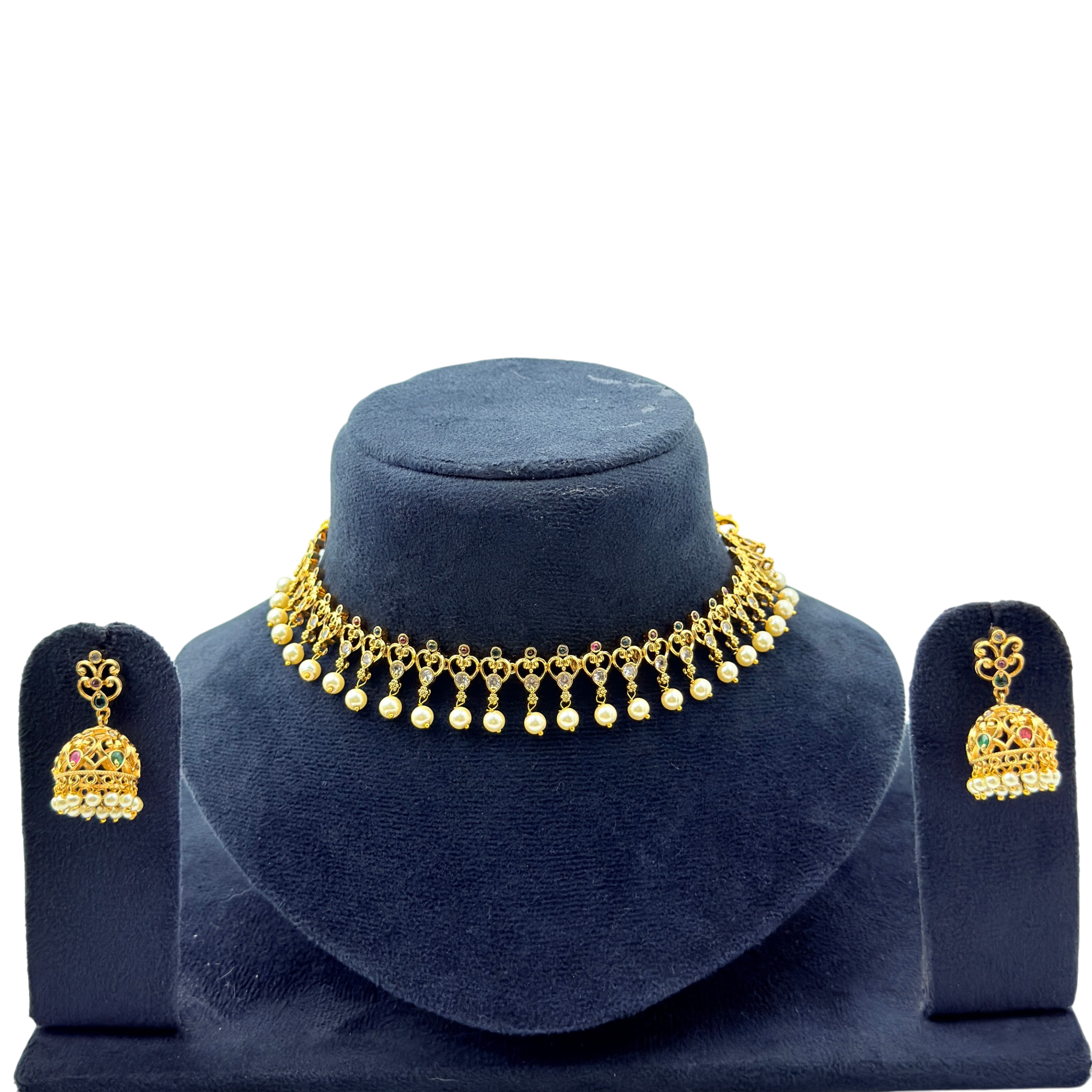 Gold necklace and earrings set on a blue velvet stand with a white background