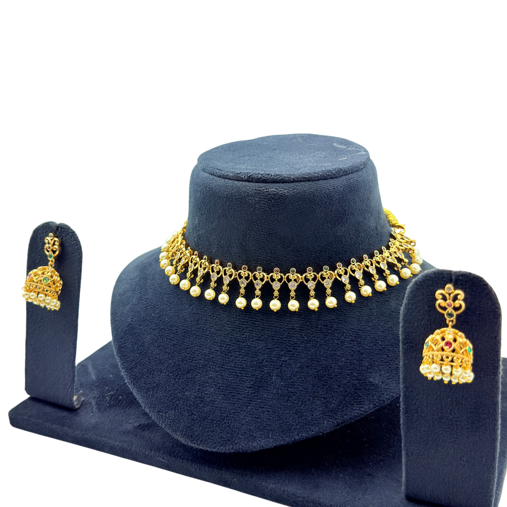 Gold necklace and earrings set on a blue stand with a white background