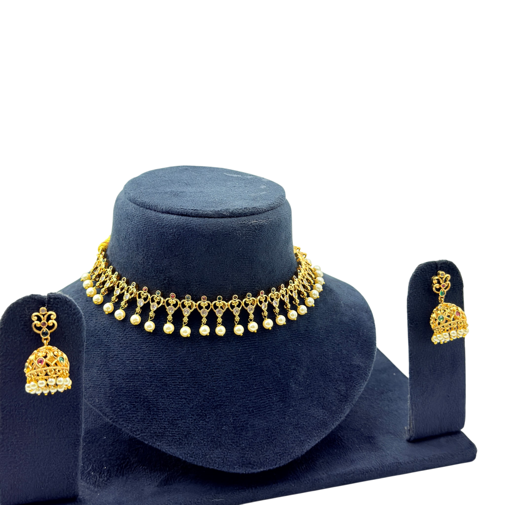 Gold necklace and earrings set on a blue velvet stand against a white background