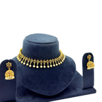 Gold necklace and earrings set on a blue velvet stand against a white background