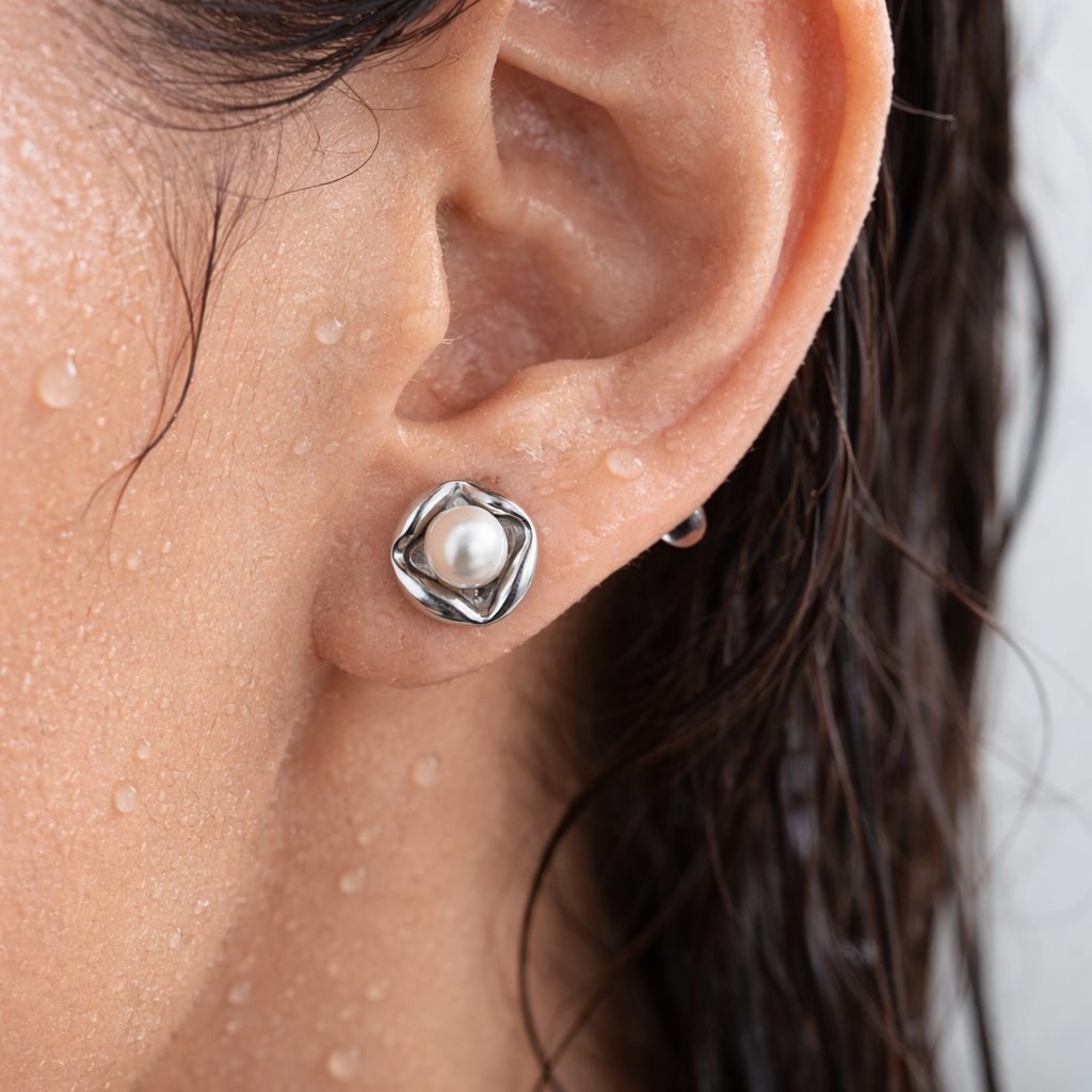 Close-up of an ear wearing a silver earring with a pearl.