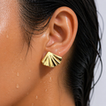 Gold shell-shaped earring worn by a person with wet skin and hair.