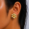 Gold flower-shaped earring worn by a person with black hair.