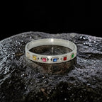 Silver bracelet with colorful gemstones on a dark textured surface