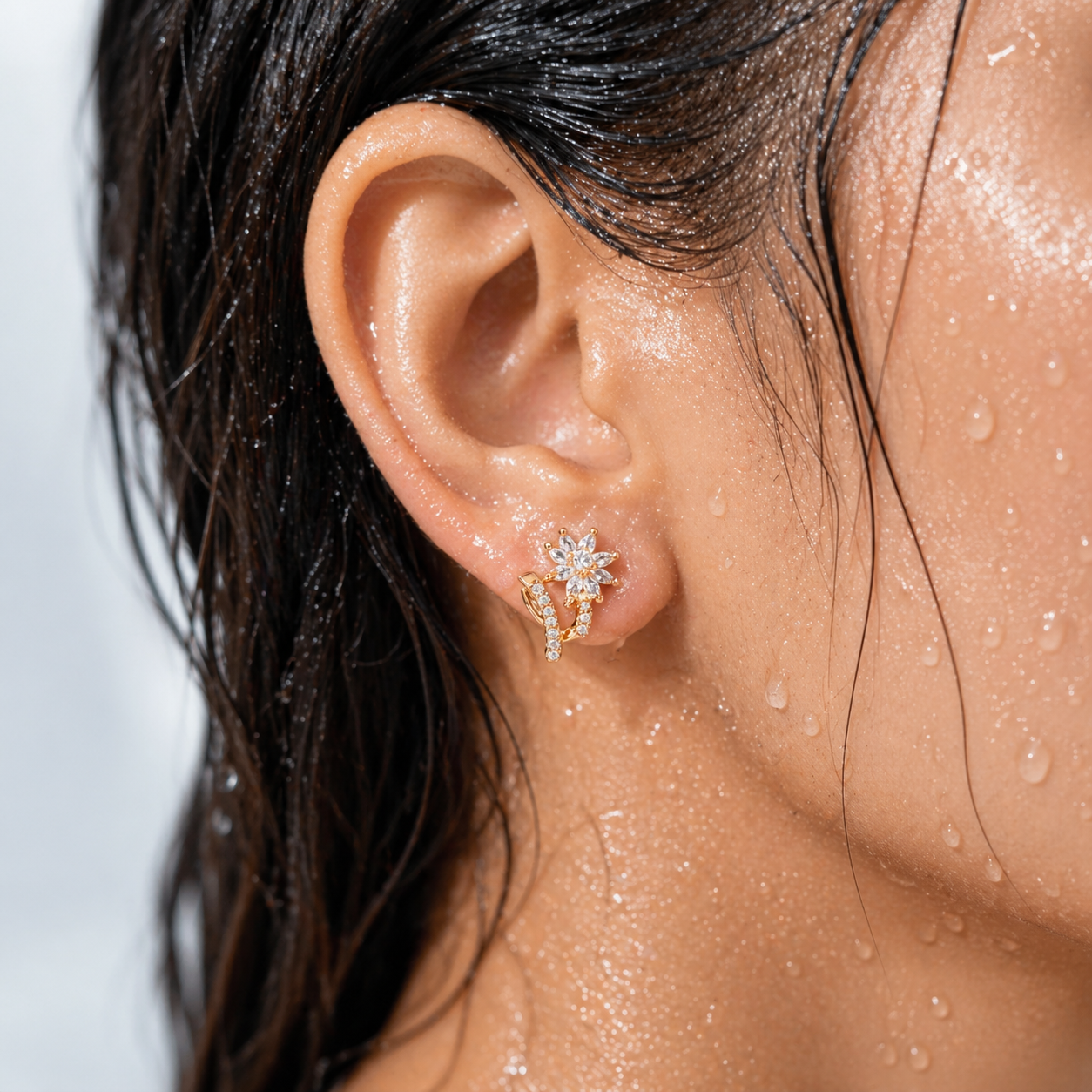 Close-up of an ear wearing a diamond earring with a blurred background