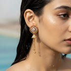 Gold halo stud drop earrings with stones and chain tassels, worn on model's ear