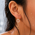 Close-up of an ear wearing a gold sunflower earring with a blurred background