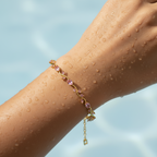 Bracelet with pink beads on a wet arm against a blue sky background