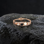 Rose gold bracelet with black and white stones on a dark textured surface