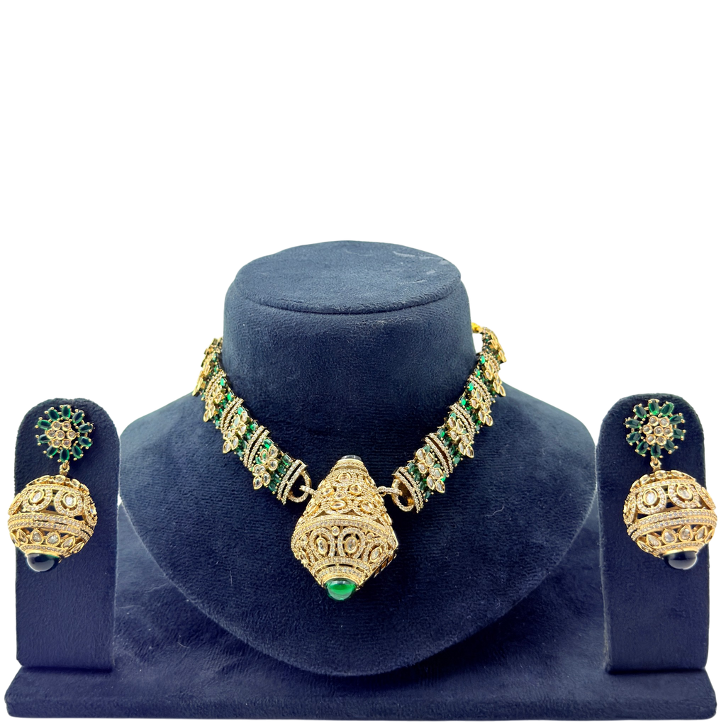 Gold and green jewelry set on a blue velvet stand with a white background