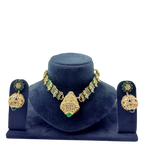 Gold and green jewelry set on a blue velvet stand with a white background