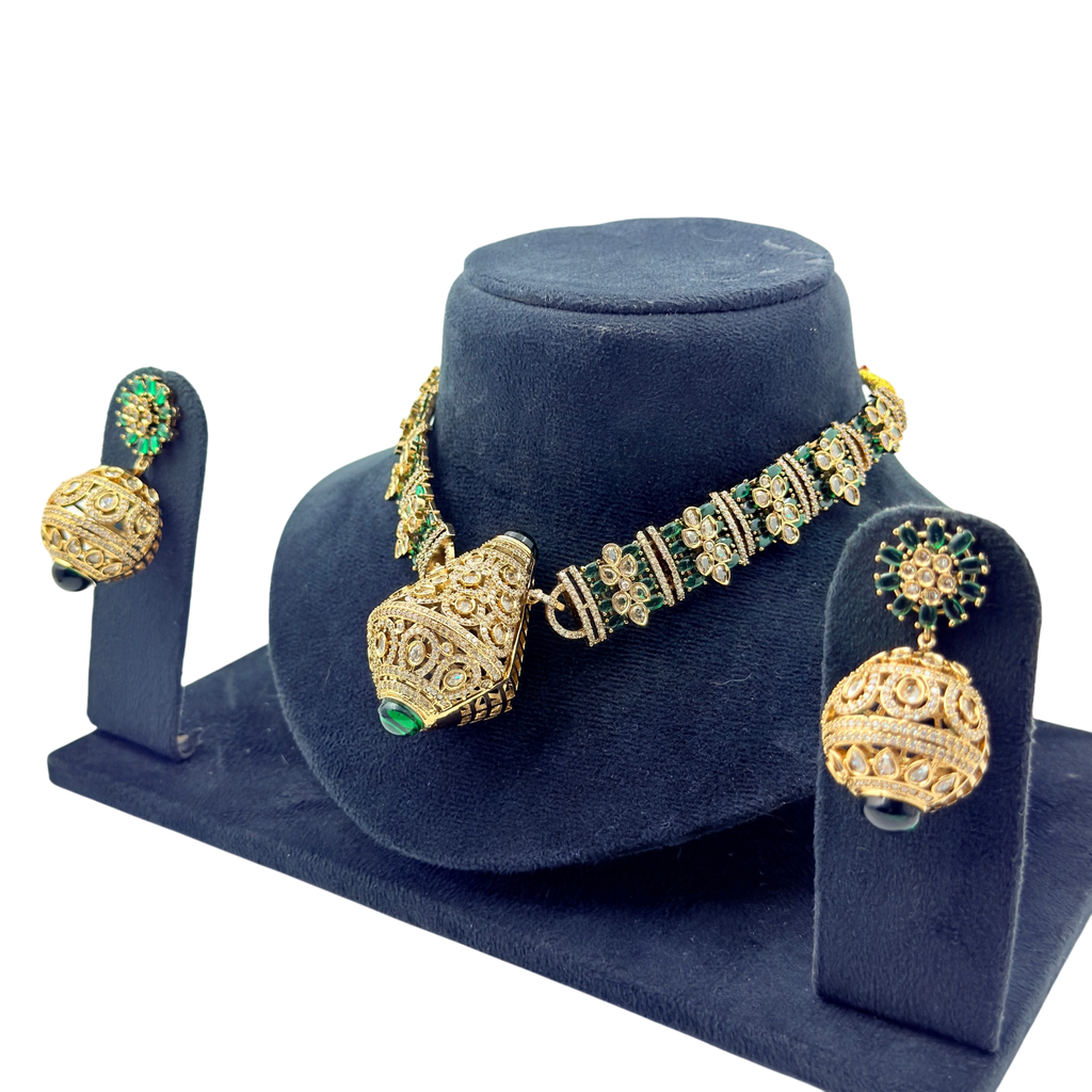 Gold and green jewelry set on a blue stand with a white background