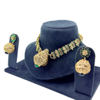 Gold and green jewelry set on a blue stand with a white background