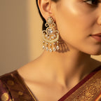Gold-tone kundan-style chandelier earring with crystal drops, worn on model's ear close-up