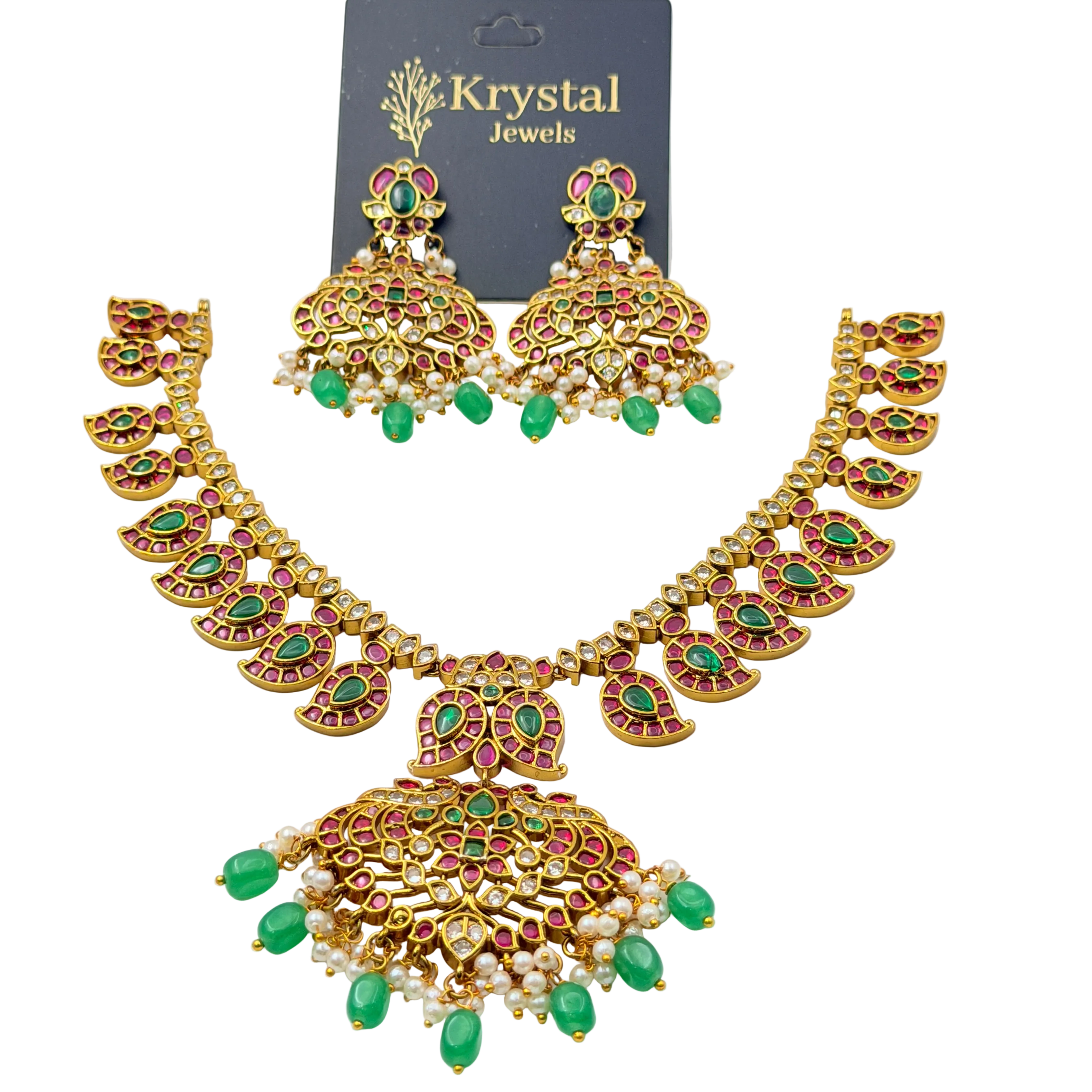 Woman wearing a gold necklace and earrings with green gemstones on a plain background