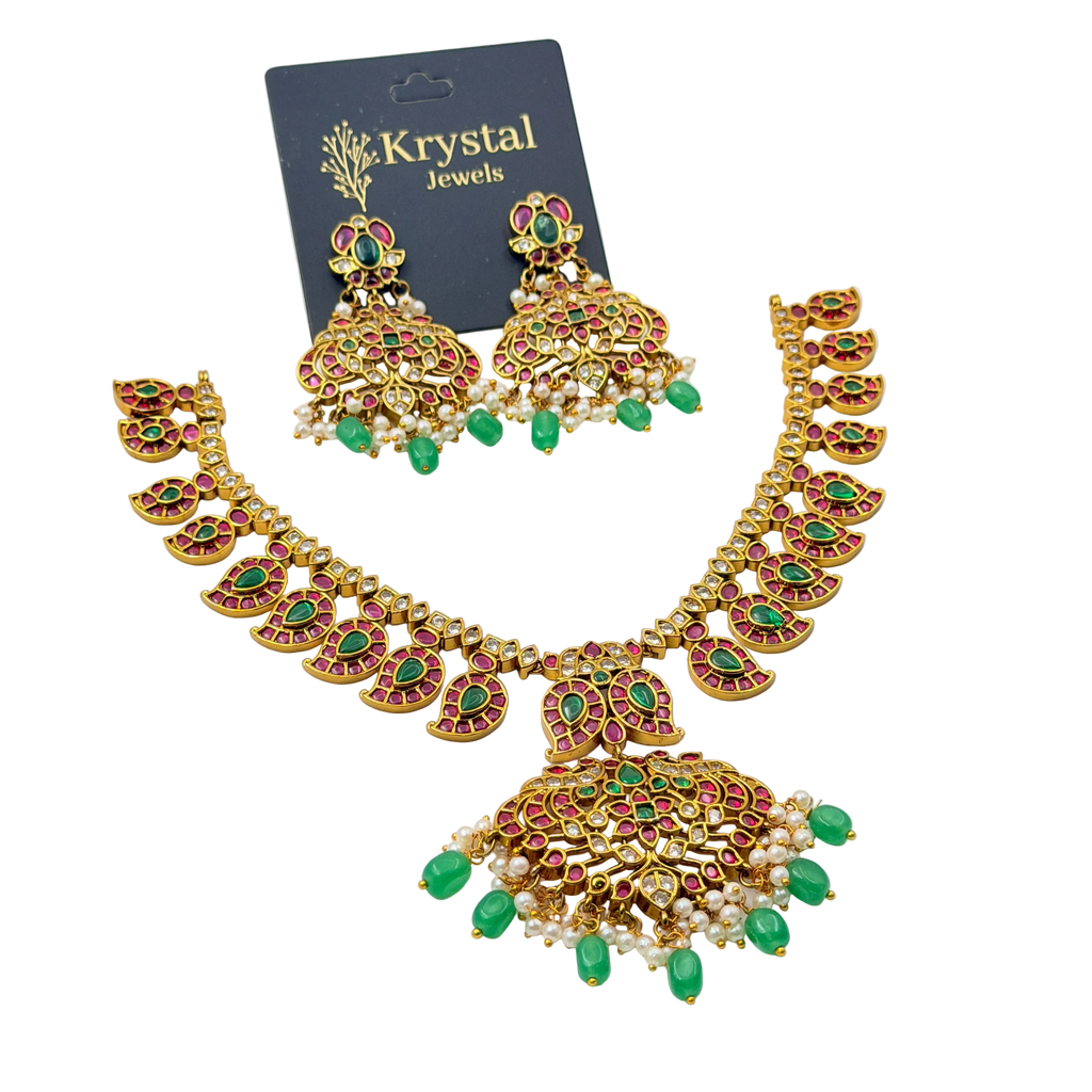 Gold necklace with green and red stones on a Krystal Jewels card