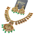Ornate necklace and earrings set with green and red stones on a clear background, branded 'Krystal Jewels'.
