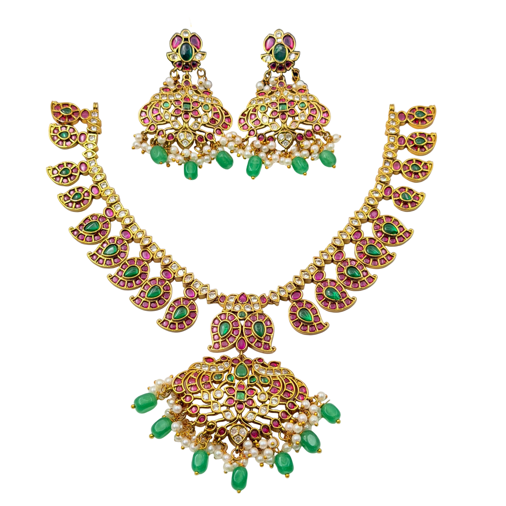 Gold necklace with green and red gemstones on a black background
