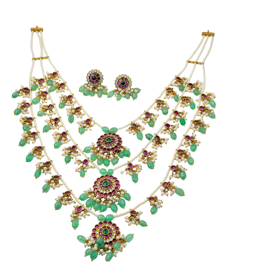 Ornate necklace with green and red gemstones on a white background