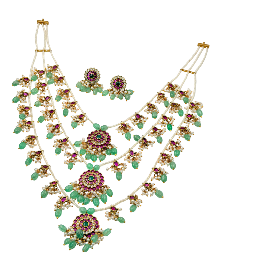 Jewelry set with necklace and earrings featuring green stones and gold accents on a white background