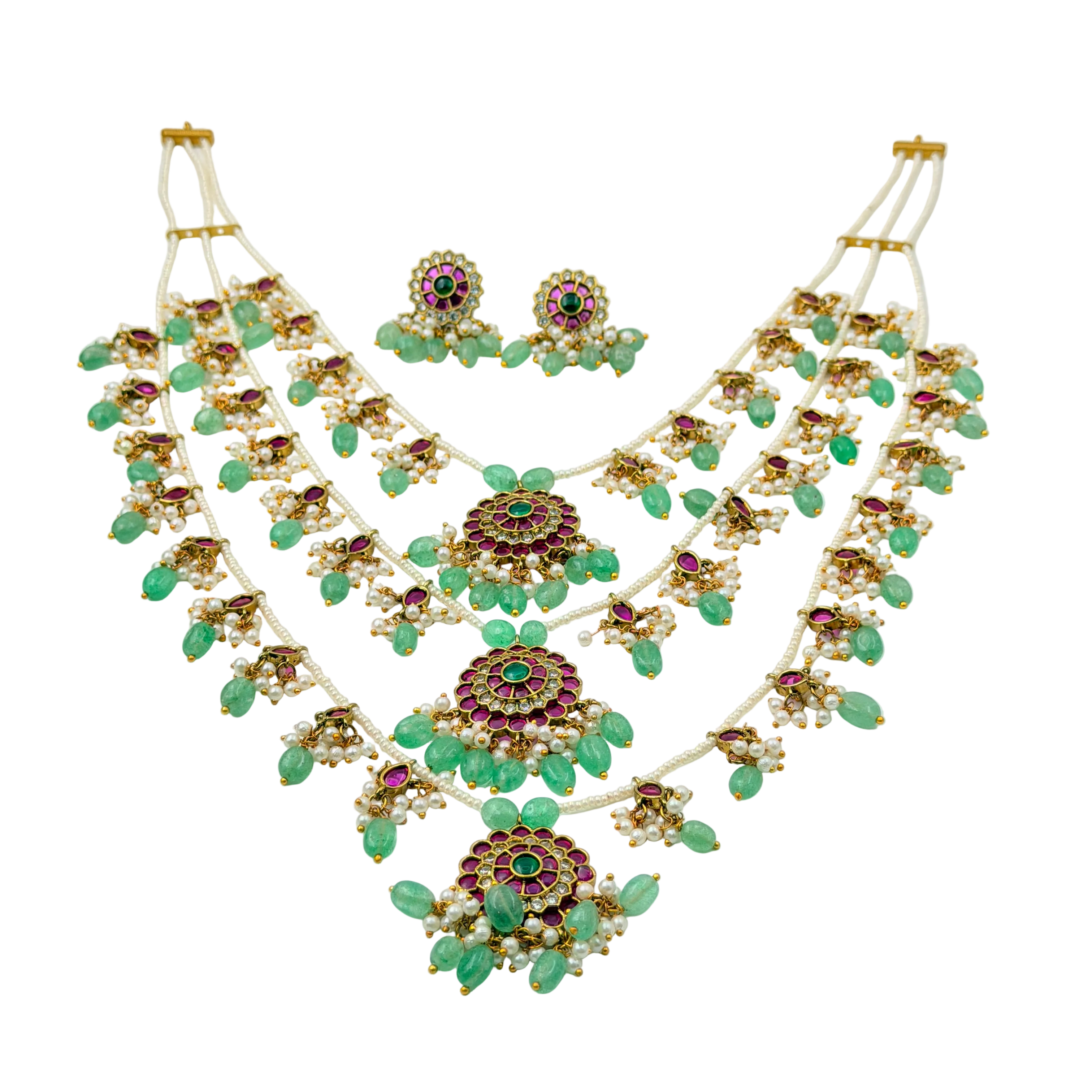 Ornate necklace and earrings set with green stones on a white background
