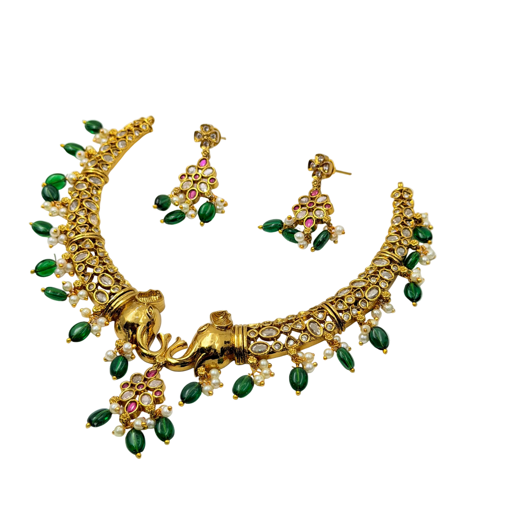 Gold necklace with green and red stones on a white background