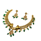 Gold necklace with green and red stones on a white background