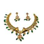 Gold necklace with green and pink stones on a white background