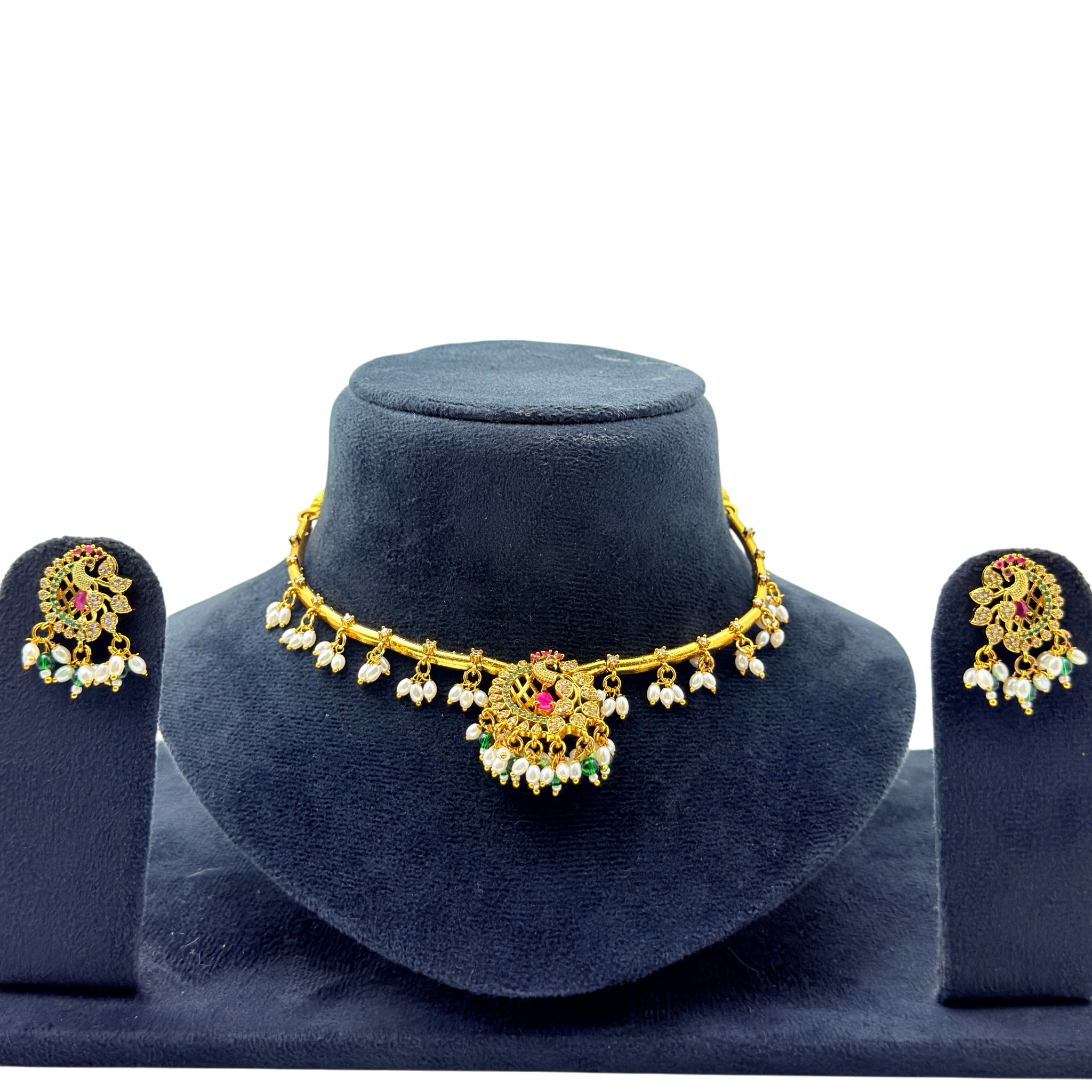 Gold necklace with pearl and gemstone details on a blue stand, accompanied by matching earrings.