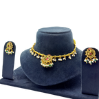 Gold necklace with floral designs and matching earrings on a blue stand against a white background