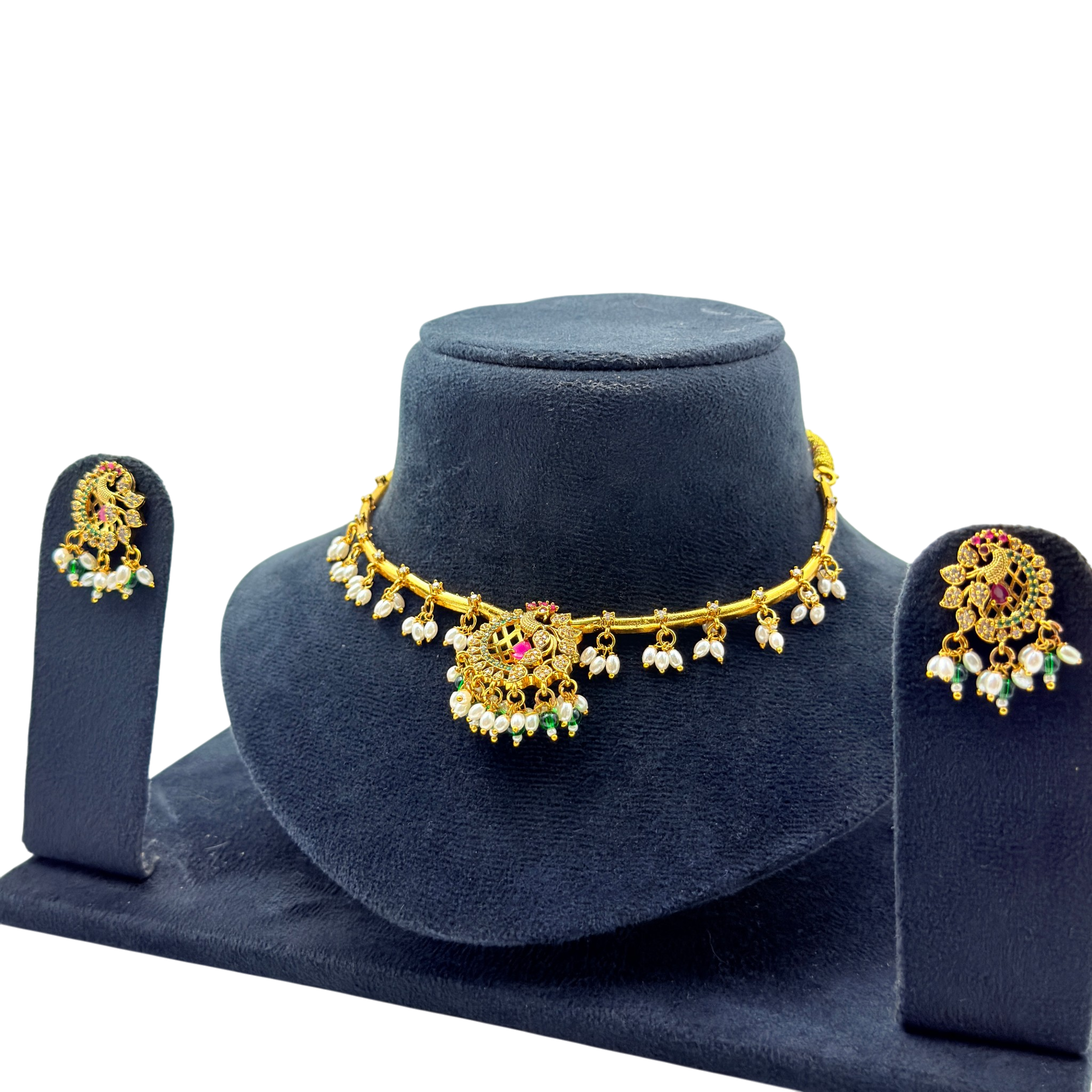 Gold necklace with floral designs and matching earrings on a blue stand against a white background